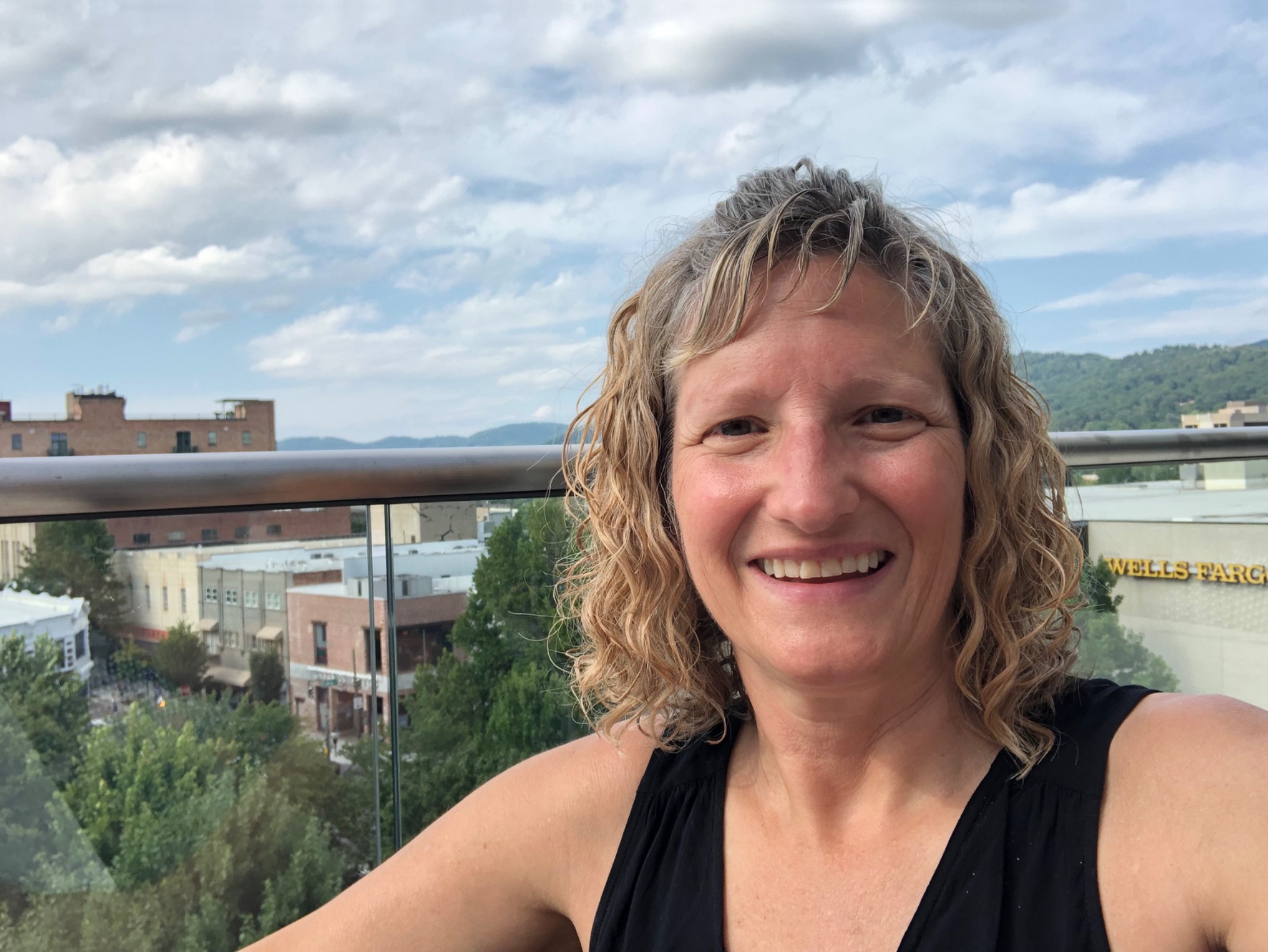 Heidi smiling outdoors with the mountains behind her